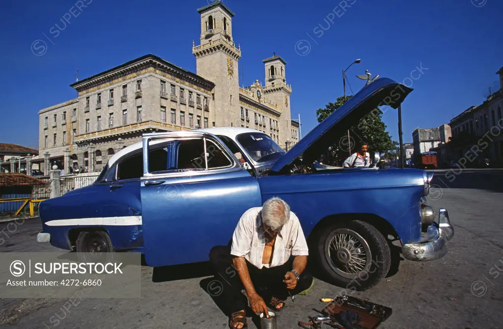 Cuban man repairing classic car in front of Havana Train Station, Havana Viejo, Old Havana World Heritage Area, Cuba