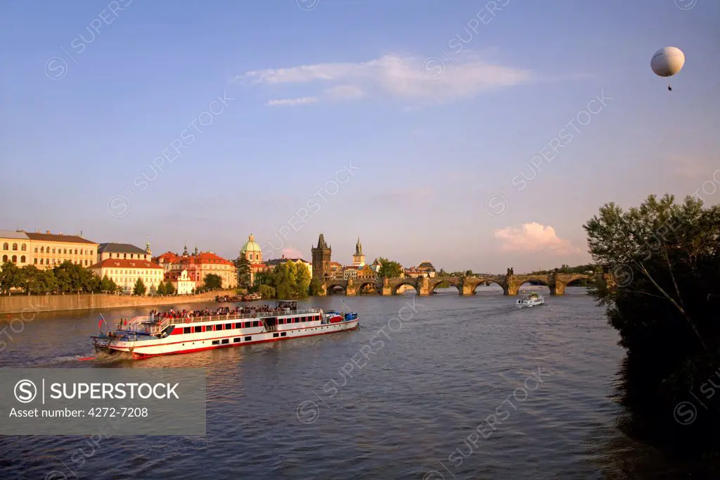 Czech Republic, Prague; A boat crossing the river Vltava and a cloudhopper viewing the city below.