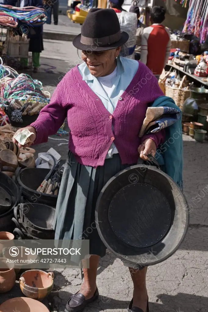 Ecuador, An old woman buys a bucket for feeding pigs made from old rubber tyres at Sangolqui market.
