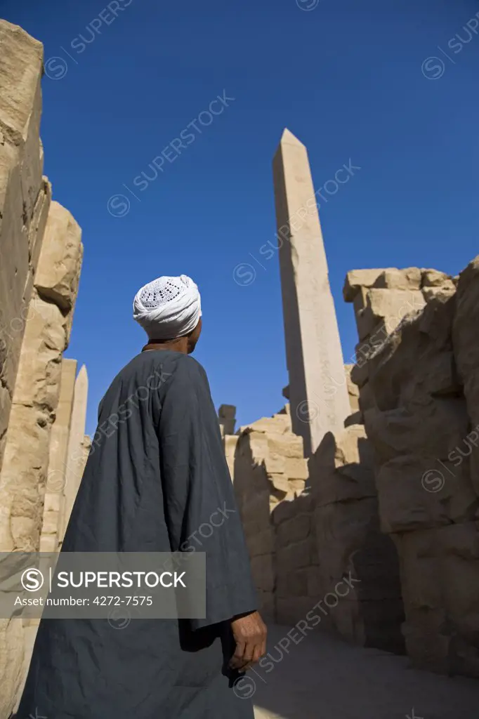 A temple guardian admires the Obelisk of Tuthmosis at Karnak Temple, Luxor.