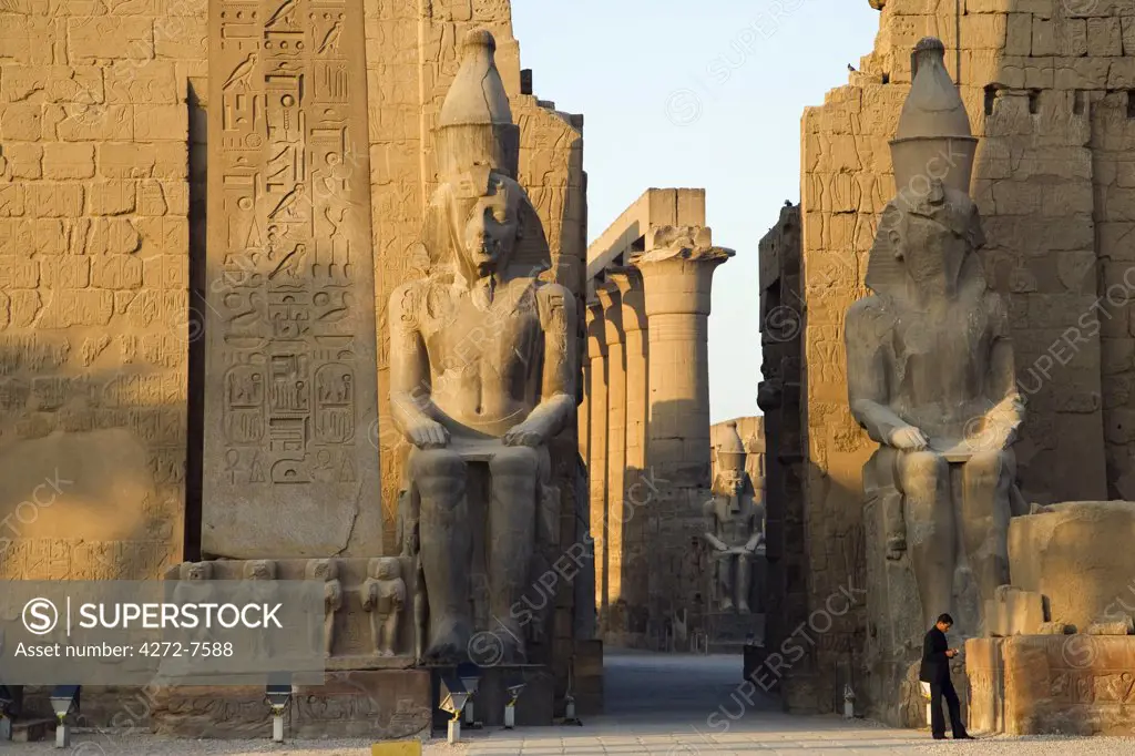 Giant statues of Ramses II stand either side of the entrance through the first pylon at Luxor Temple, Egypt
