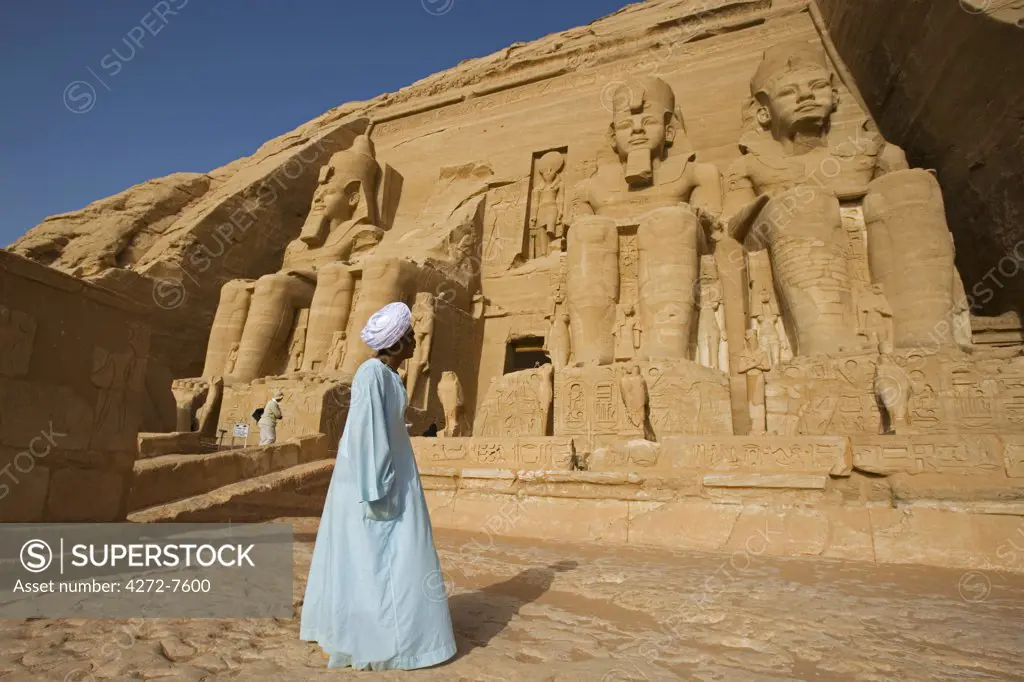 A temple guardian stands in front of the facade of Abu Simbel. The entire site was moved 200m in the 1960s in order to save it from the rising waters of Lake Nasser, Egypt