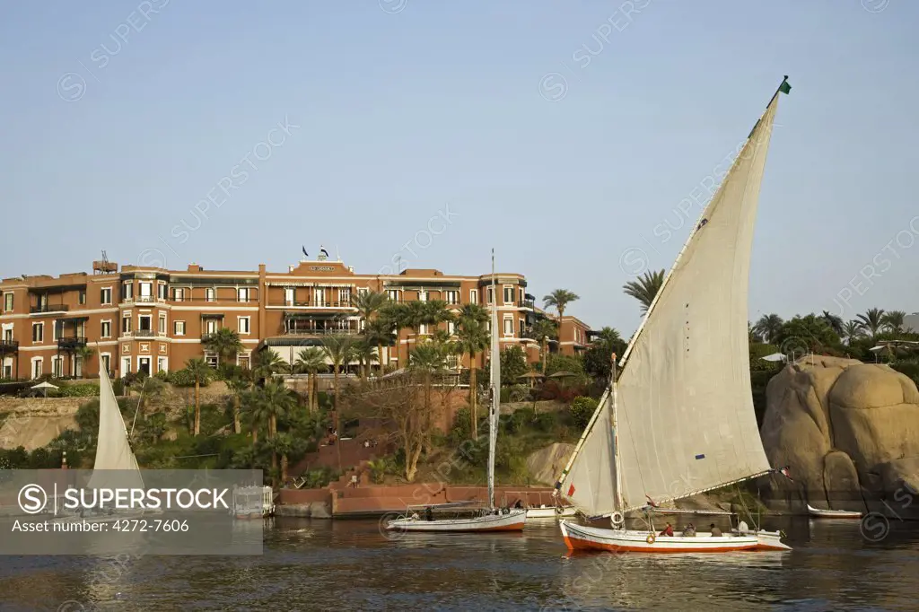 Feluccas sail in front of the luxurious Old Cataract Hotel at Aswan, Egypt.
