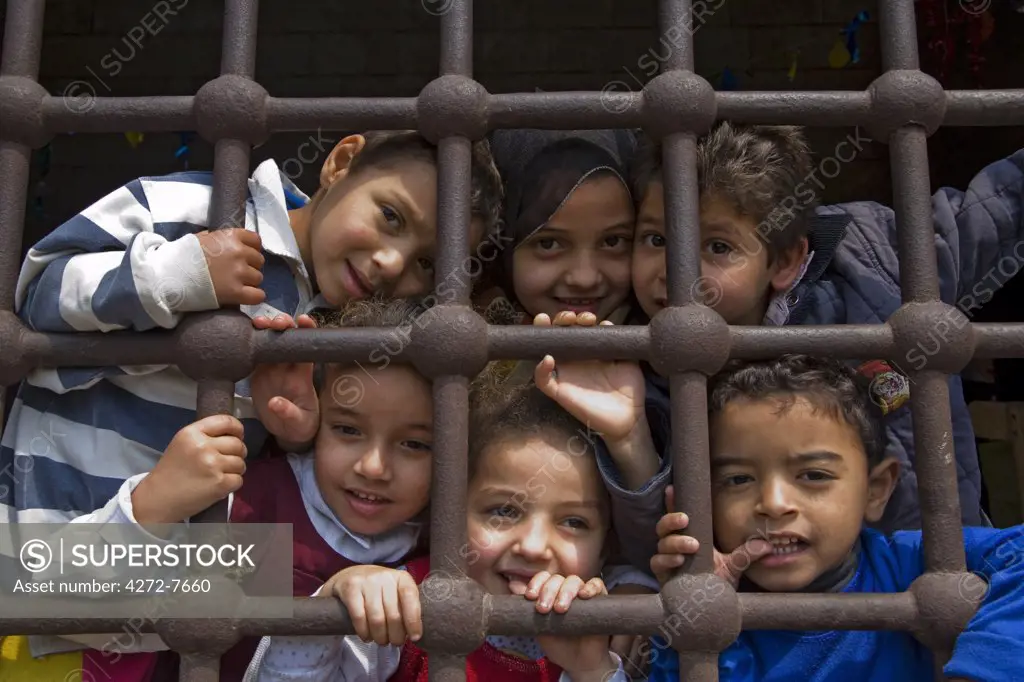 Curious children peer through the window of their classroom housed in an old Mamluk building in Islamic Cairo, Egypt
