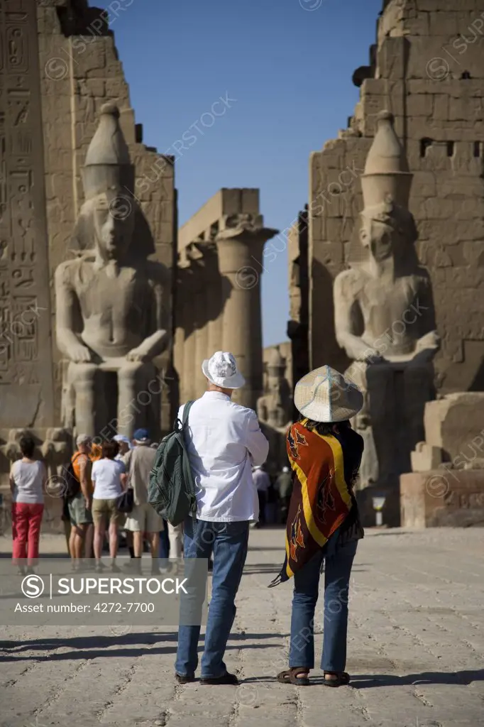 A couple admire the enormous first Pylon of Luxor Temple, Egypt.