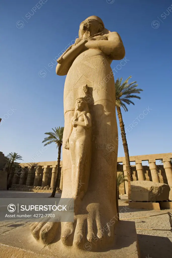 A colossal statue of Ramses II with his daughter Benta-anta at his feet stands in the Great Forecourt of Karnak Temple, Luxor, Egypt
