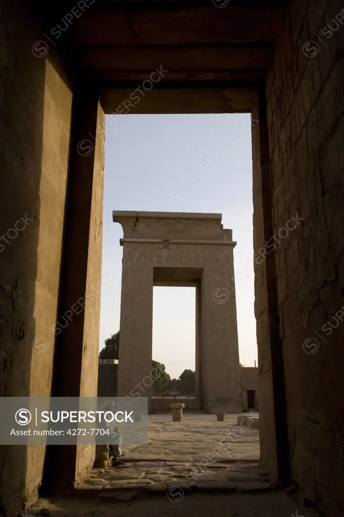 A temple guardian peers through the monumental doorway of the Temple of Khonsu at Karnak Temple, Luxor, Egypt