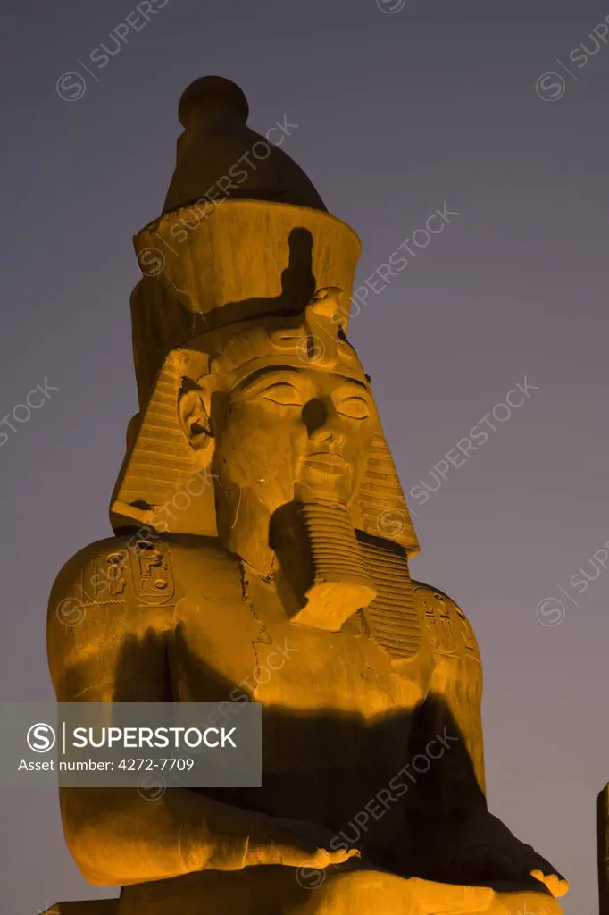 A larger than life statue of Ramses II illuminated at night in Luxor Temple, Egypt