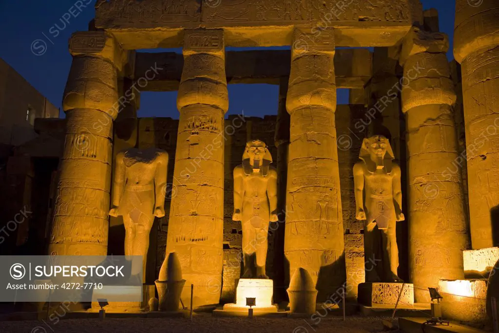 Larger than life statues of Ramses II illuminated at night in Luxor Temple, Egypt
