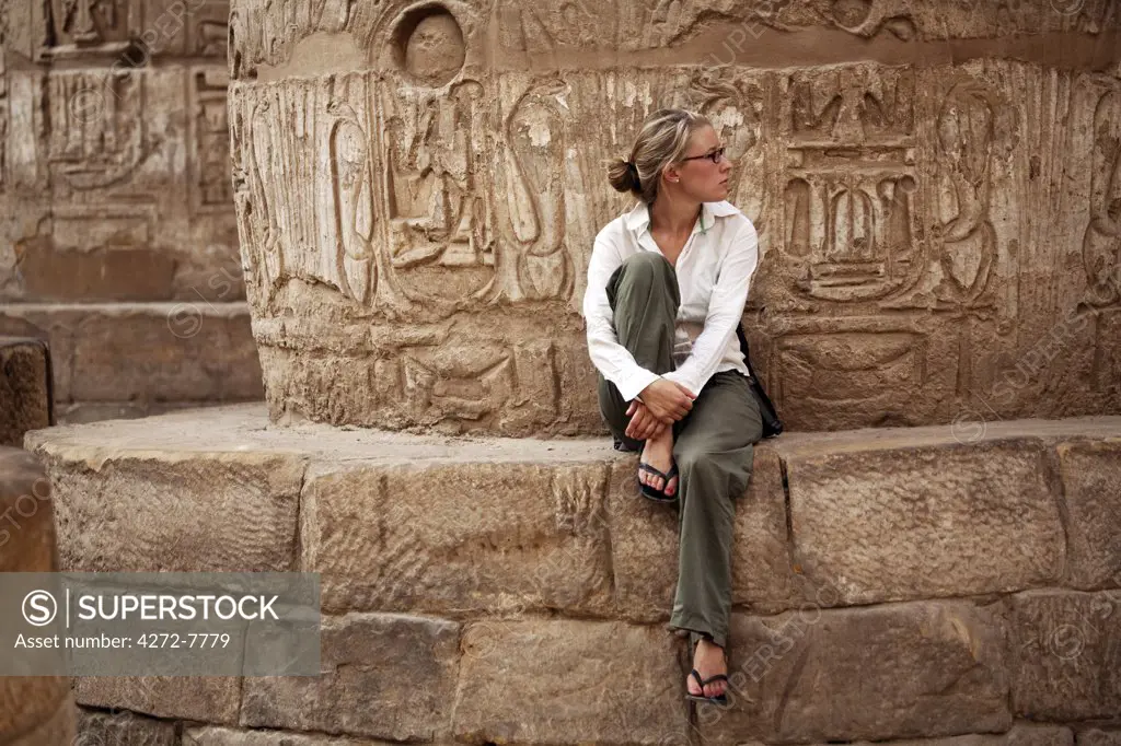 Egypt, Karnak. A tourist sits at the base of a massive stone column in the Great Hypostyle Hall. (MR)