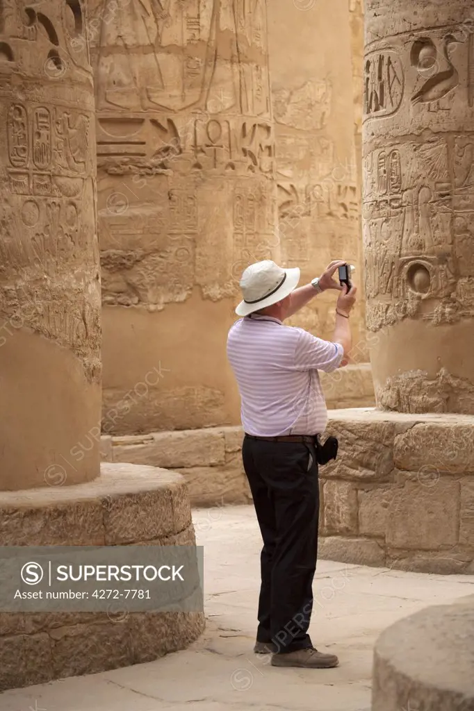 Egypt, Karnak. A tourist photographs the massive stone columns in the Great Hypostyle Hall.