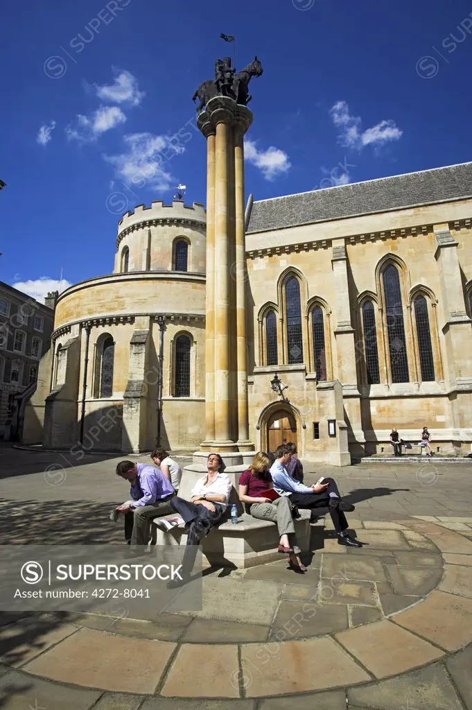 Office workers relaxing in the sunshine outside Temple Church, London. Temple Church is a late 12th century church originally constructed as part of a monastic complex known as the Temple, the headquarters in England of the Knights Templar. It was heavily damaged during the Second World War but has been largely restored. It was featured in the Da Vinci Code by American author Dan Brown, now made into a film starring Tom Hanks.
