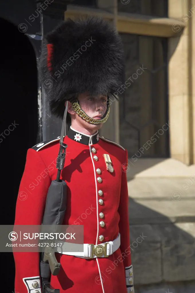 A guard wearing a traditional bearskin stands guard outside the Jewel House in the Tower of London.