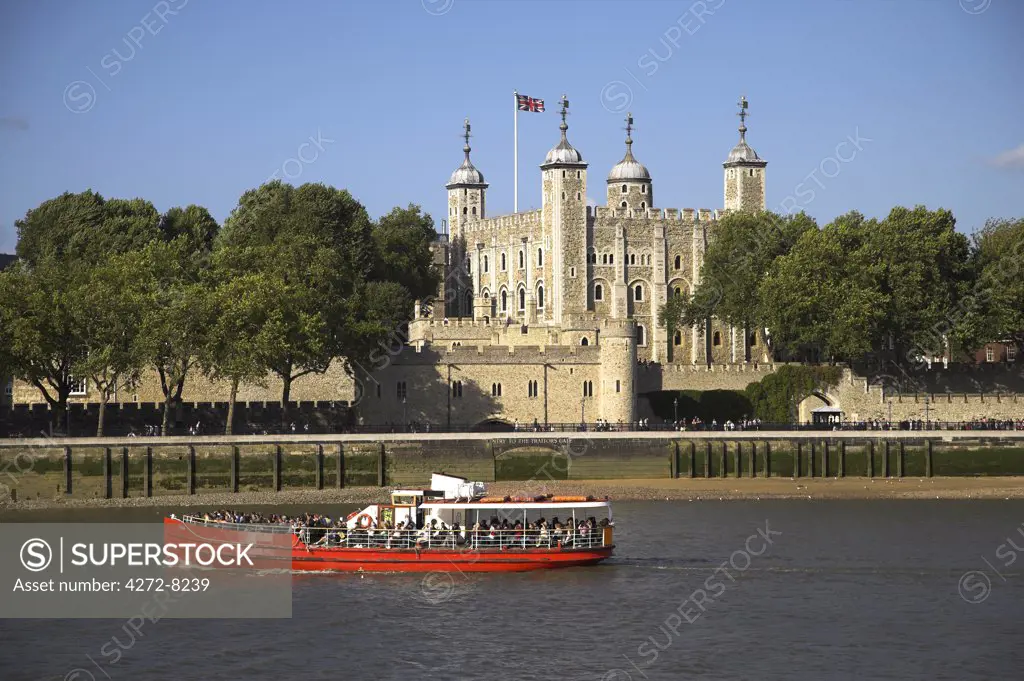A tour boat on the River Thames passes the Tower of London. The original entrance to Traitor's Gate can be seen on the waterline.