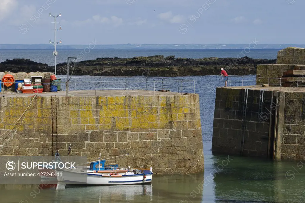 Fishing boats tethered within the safety of the massive harbour wall protecting the harbour of Mousehole, Cornwall, England