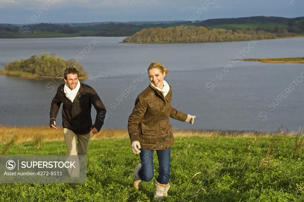 UK, Northern Ireland, Fermanagh. Couple chasing each other on a walk at Lough Erne (MR).