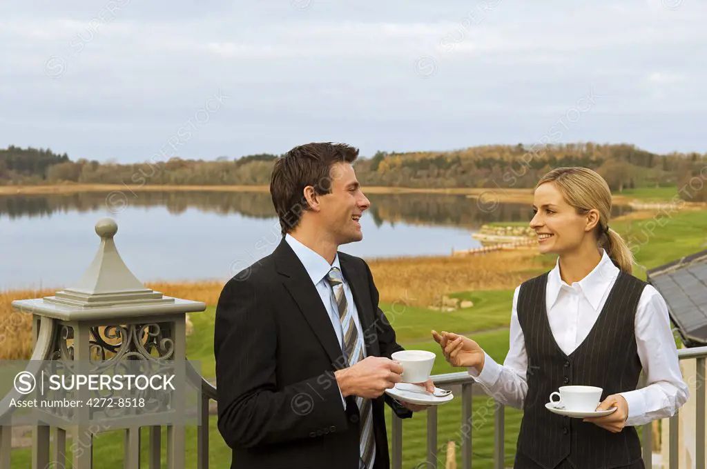 UK, Northern Ireland, Fermanagh, Enniskillen. Two business people have an informal meeting on the verandah of the Fermanagh Suite at the Lough Erne Golf Resort (MR).