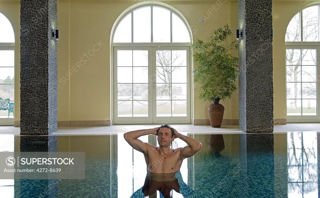 Northern Ireland, Fermanagh, Enniskillen. A man enjoys a swim in the indoor swimming pool at Lough Erne Golf Resort (MR).