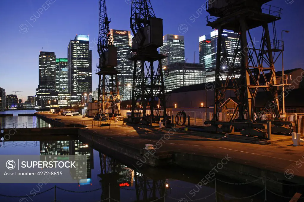 England, London, Cranes at the london docklands with canary wharf business district in the background.