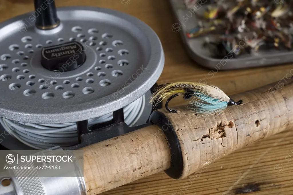 UK.  A salmon fly stuck into the cork handle of a fly fishing rod.
