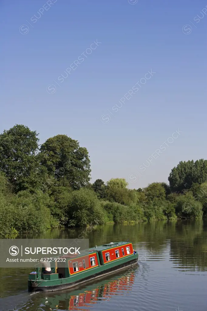 England, Shropshire, Severn Valley. A longboat makes it way down the River Severn on a fanstatic summer day.