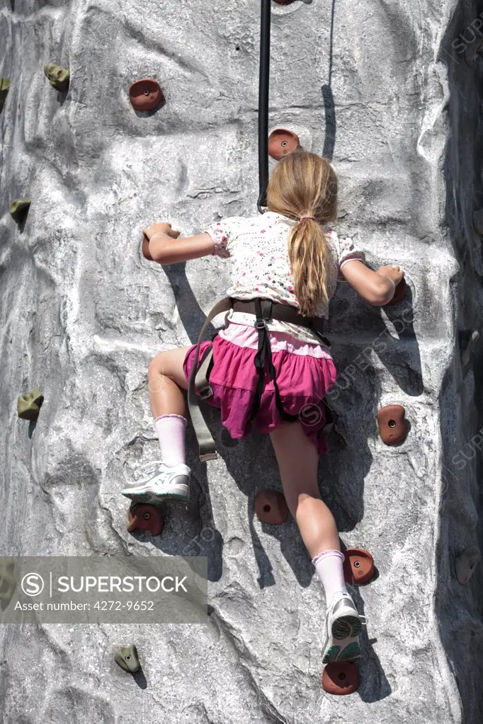 England, Devon, Woolacombe. Young girl scaling an artifical rock-climbing wall at Woolacombe Bay Holiday Park. (MR)