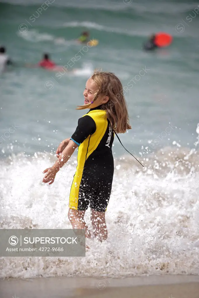 England, Cornwall. A young girl plays in the surf at Whitesand Bay, Sennen Cove. (MR)