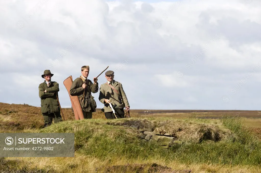 UK; Yorkshire.  A keeper points out the lay of the land whilst grouse shooting on Bingley Moor.