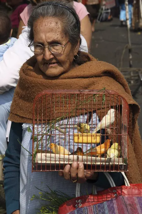 Mexico, Mexico City. An old woman selling birds at a traditional market in Mexico City.