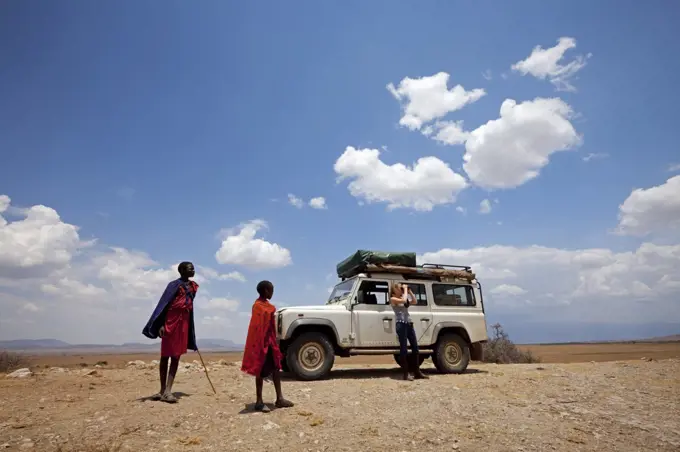 Tanzania, Olduvai. Maasai children watch as a tourist looks out over the landscape around Olduvai gorge. MR.