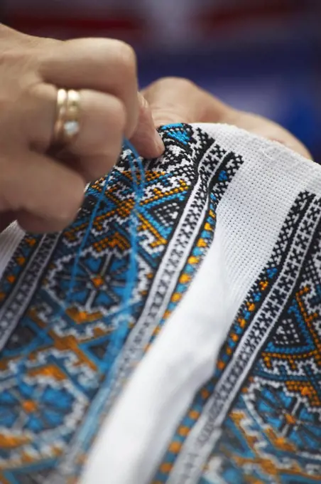 Woman sewing traditional pattern onto cloth at Craft Market, Lviv, Ukraine