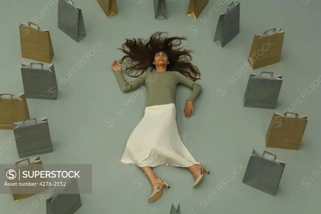 Woman lying on the ground, surrounded by shopping bags