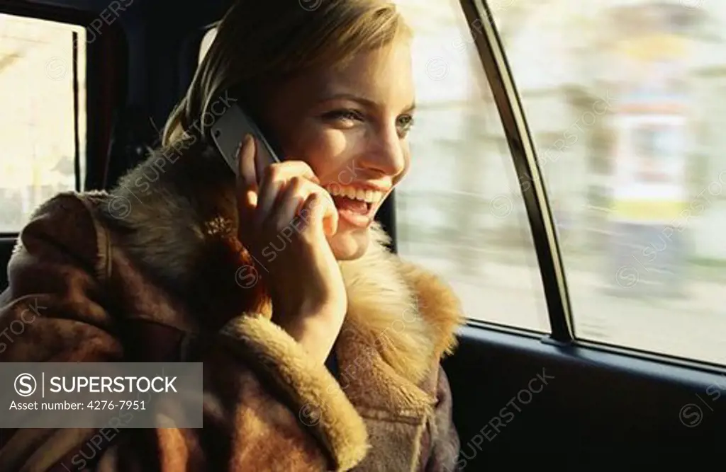 Young woman using cell phone in car