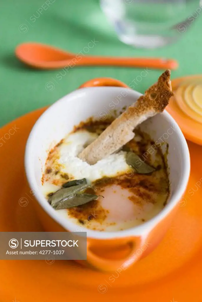 Oeufs en cocotte with herbs and spices, served with sliced bread strip