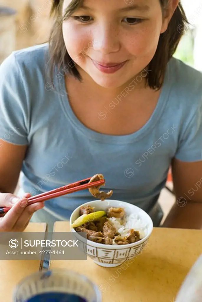 Girl eating food using chopsticks