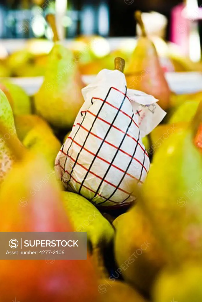 Fresh ripe pears, one wrapped in tissue paper