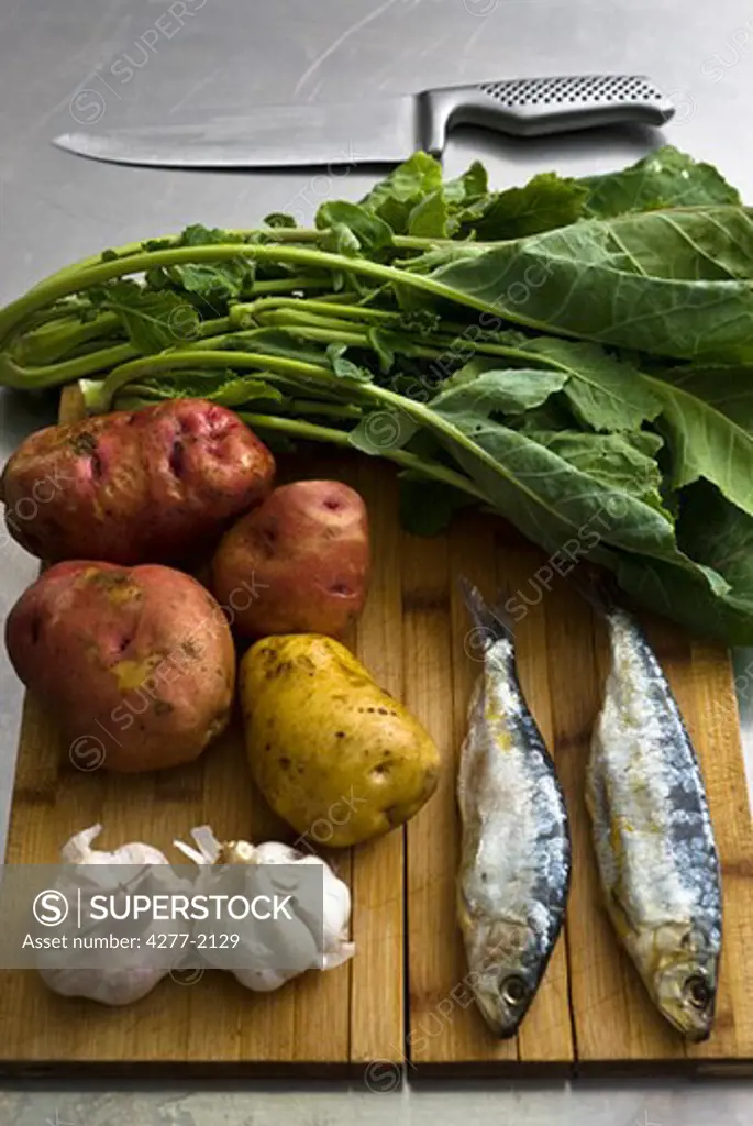 Fresh raw sardines and vegetables on cutting board