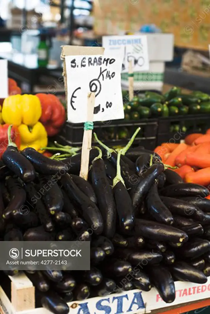 Fresh eggplants and other produce in outdoor market