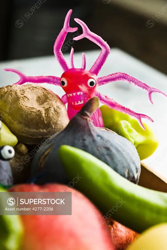 Toy monster in bowl of fresh vegetables and fruit