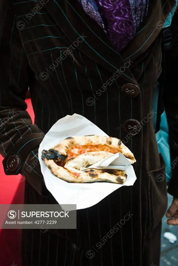 Person holding folded pizza