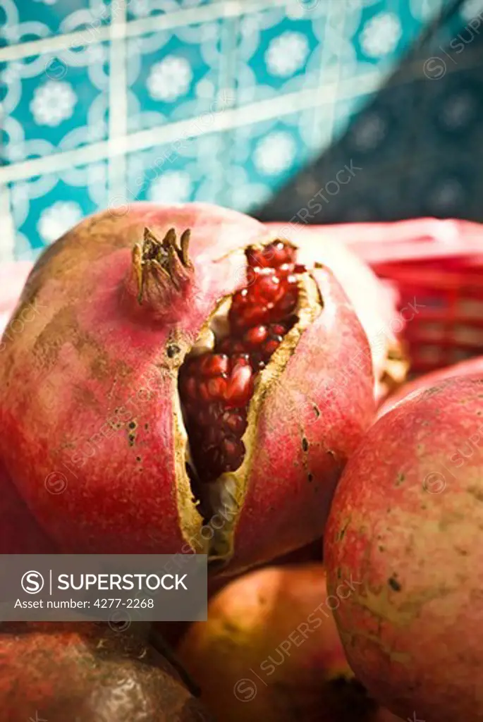Fresh pomegranates, one cracked open revealing seeds