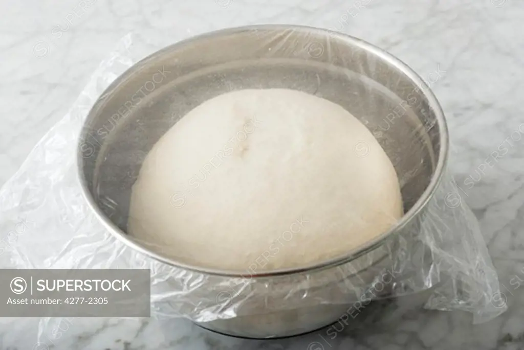 Basic bread dough rising in covered bowl