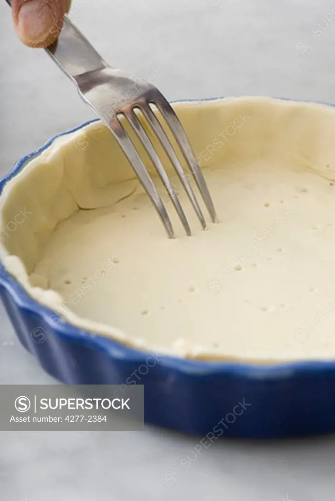 Poking shortcrust pastry dough with fork