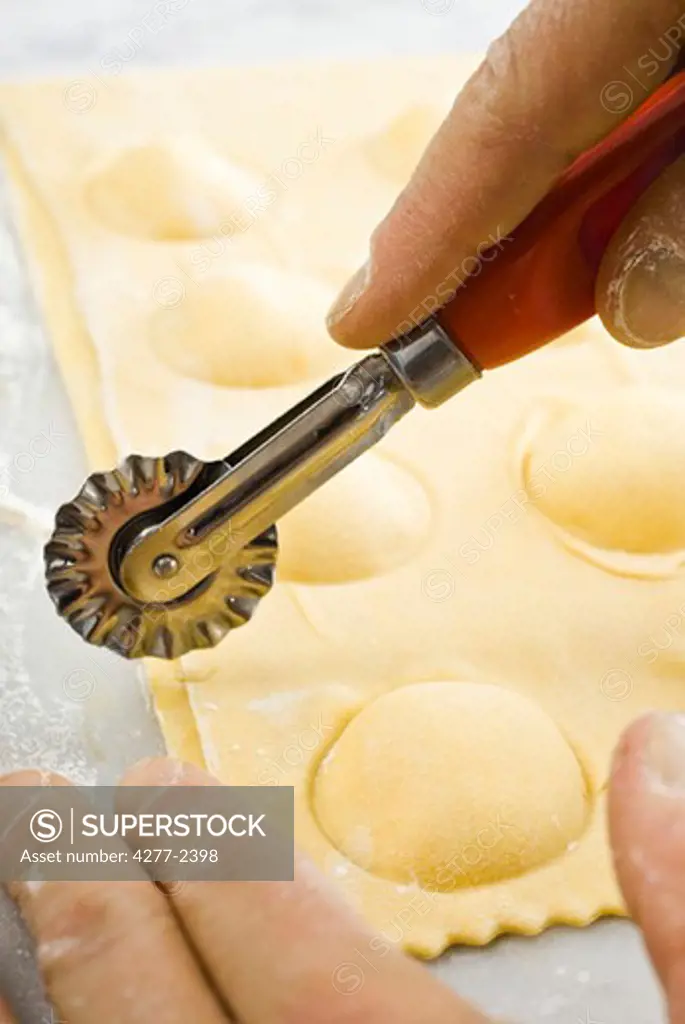 Cutting fresh ricotta ravioli with pastry wheel