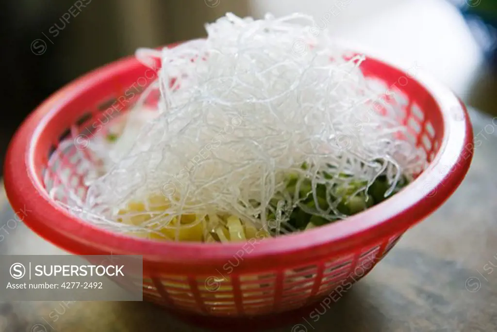 Rice vermicelli and other ingredients in colander