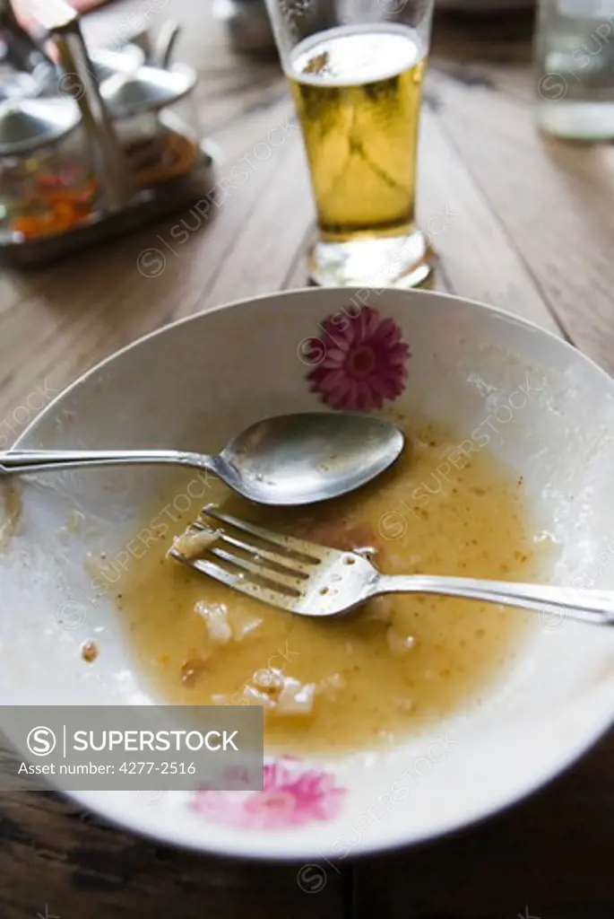 Bowl and utensils left on table after meal