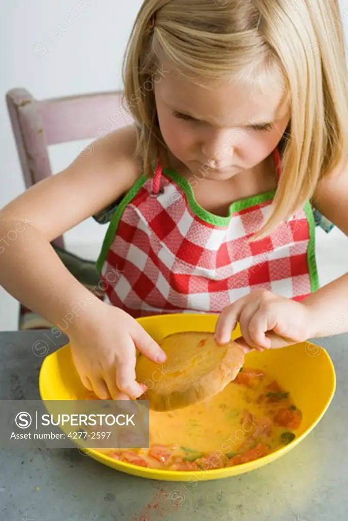 Little girl dipping bread in egg batter