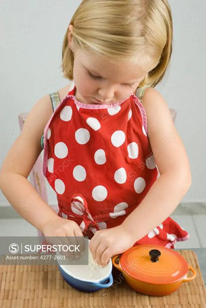 Little girl greasing small casserole dish