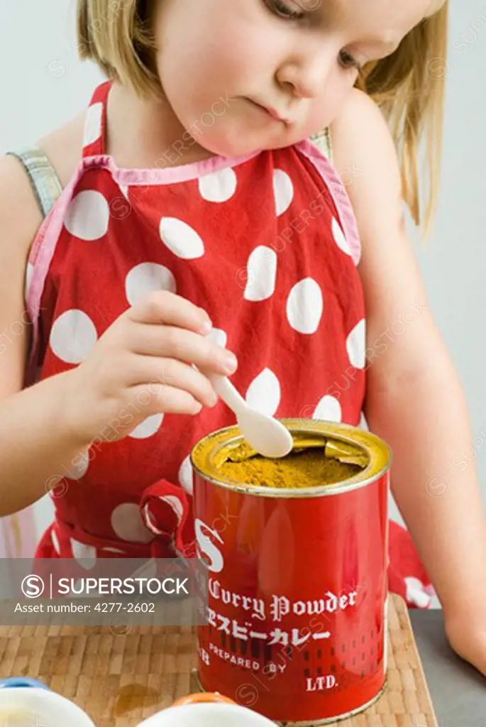 Little girl scooping curry powder from can