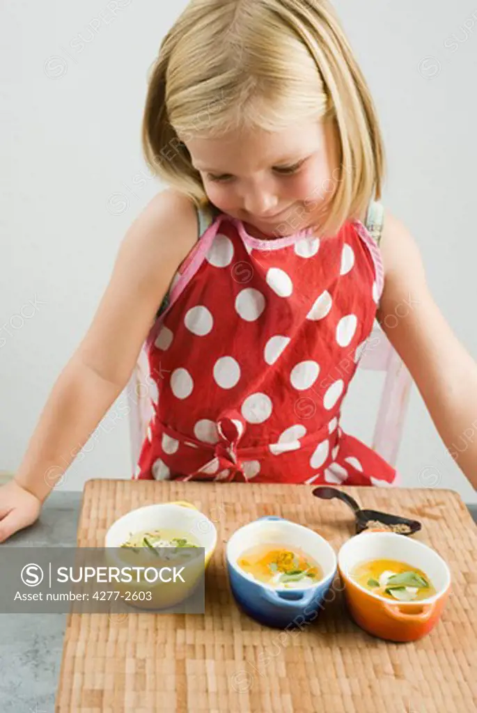 Little girl preparing baked eggs in small casserole dishes